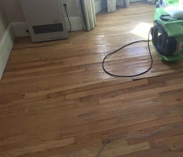 Buckled wood flooring with SERVPRO equipment on the floor. 