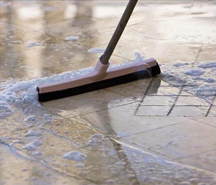 Broom sweeping standing water on floor